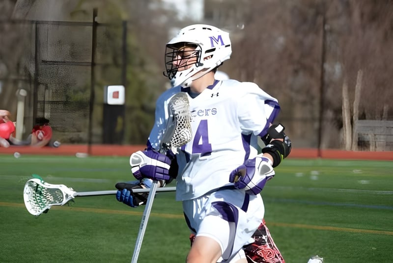 Un jugador de lacrosse con el número 4 en uniforme blanco en el campo de deportes de The Masters School.