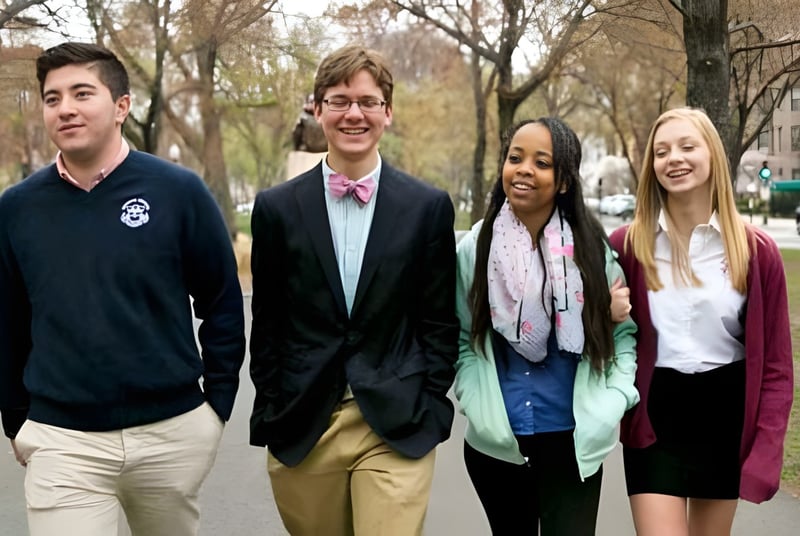 Cuatro estudiantes de The Newman School caminan juntos por una calle flanqueada de árboles.