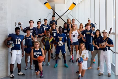 Un grupo de jóvenes atletas posan juntos en el gimnasio de The Peddie School con equipo deportivo de fondo.
