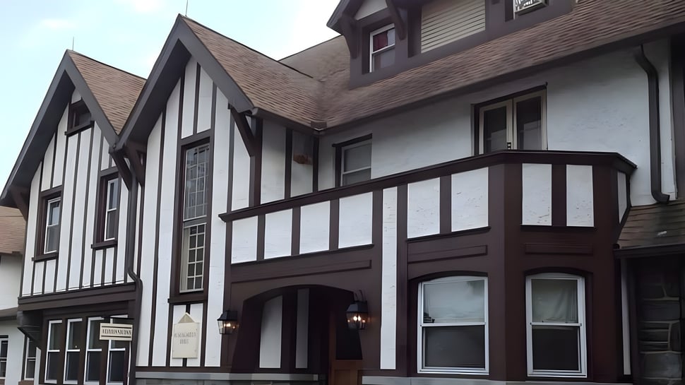 El edificio Tudor de varios pisos con fachada exterior de madera y ventanas de saliente en el campus de The Phelps School.