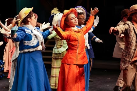 Un grupo de bailarines en coloridos trajes realiza una actuación en el escenario de The Stony Brook School.