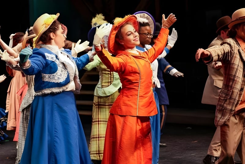 Un grupo de bailarines en coloridos trajes realiza una actuación en el escenario de The Stony Brook School.