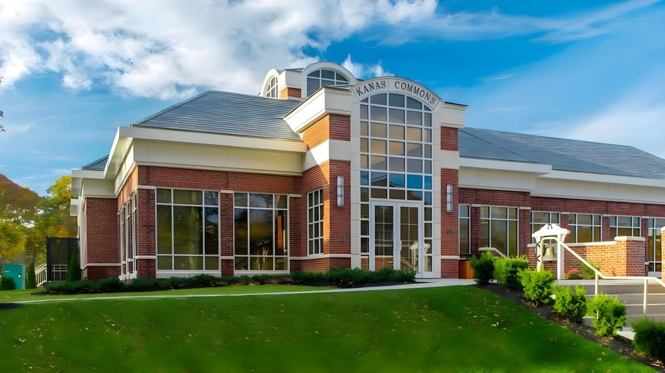 El moderno edificio de varios pisos de The Stony Brook School con zona de entrada acristalada y césped bien cuidado.