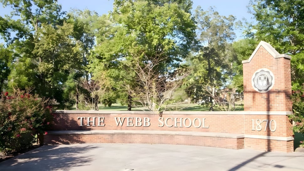 El cartel de entrada de ladrillo de The Webb School está rodeado de plantas y árboles verdes.