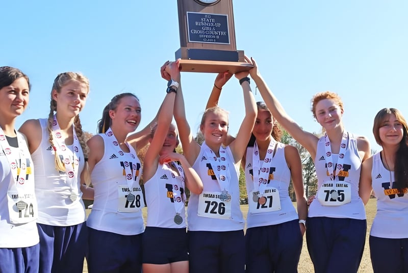 El equipo femenino de The Webb School sostiene juntos un trofeo bajo un cielo azul.