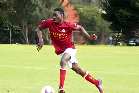 Una persona corre en un campo de hierba en el campus del Thebarton Senior College frente a árboles.
