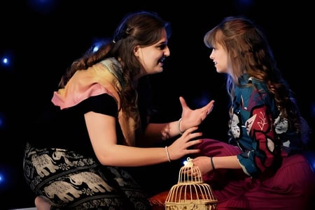 Dos estudiantes de la Thetford Grammar School se abrazan frente a un fondo oscuro con luces brillantes.