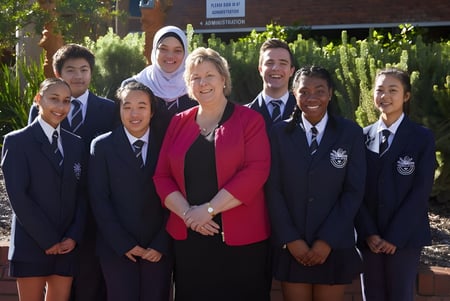 Un grupo de estudiantes está frente a un edificio de ladrillo en el campus de la Thornlie Senior High School.