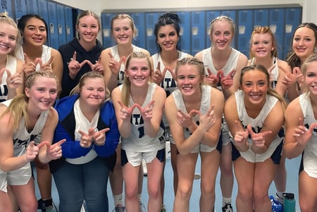 Un grupo de jóvenes estudiantes del equipo deportivo de la Thunder Ridge High School posan en un vestuario frente a taquillas.