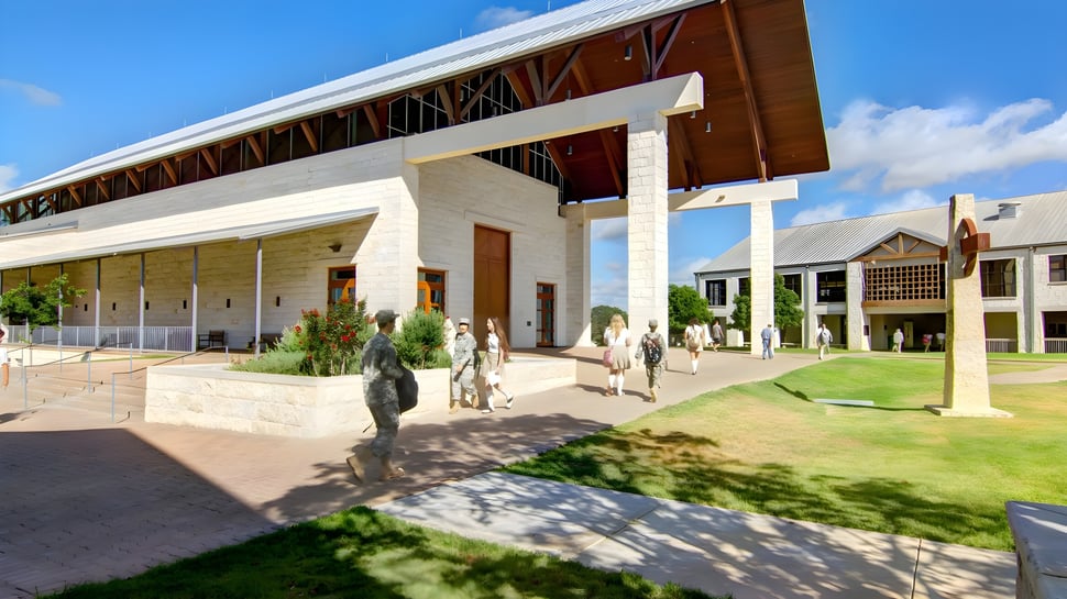 El moderno edificio escolar de TMI Episcopal con elementos de madera y piedra en un entorno exterior bien cuidado.
