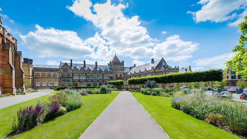 Un jardín bien cuidado con un camino sinuoso lleva a un edificio similar a un castillo en el terreno de la Tonbridge School.