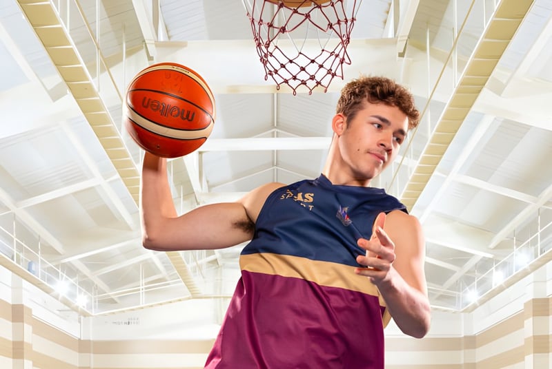 Un estudiante de la Toowoomba Anglican School sostiene un baloncesto en el gimnasio bien iluminado.