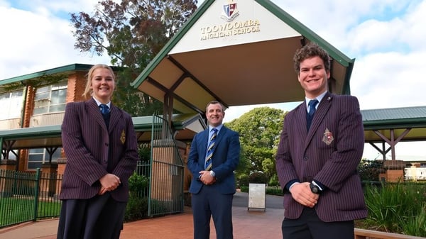 Tres estudiantes de la Toowoomba Anglican School están frente a un edificio con el letrero Royal College of Music.