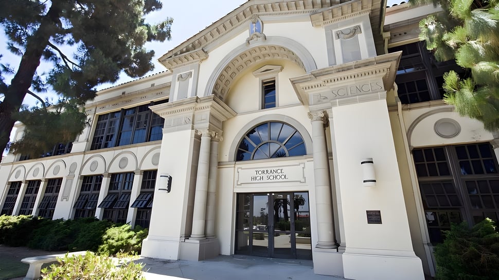 El histórico edificio curvado de la Torrance High School está rodeado de árboles.