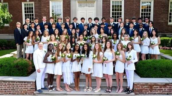 Un grupo de estudiantes de la Tower Hill School está junto a un edificio de ladrillo con columnas.
