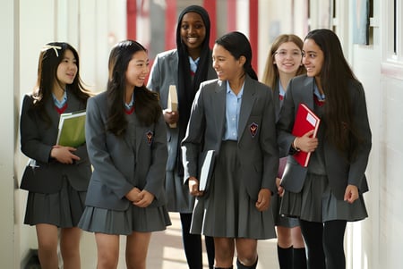 Las estudiantes y estudiantes de la Townley Grammar School caminan juntos por un pasillo con paredes rojas.