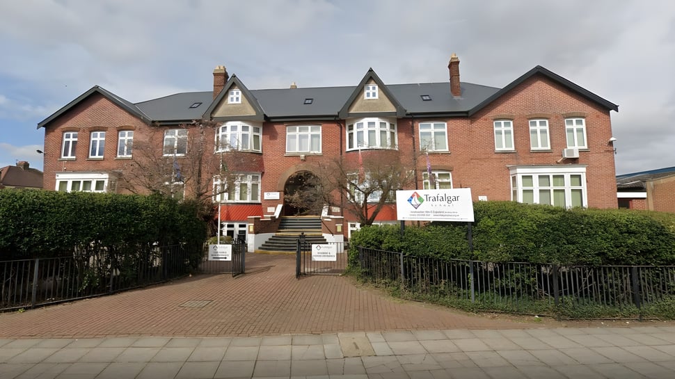 El edificio de ladrillo de varios pisos con ventanas de arco y techo de tejas se encuentra en el campus de la Trafalgar School.