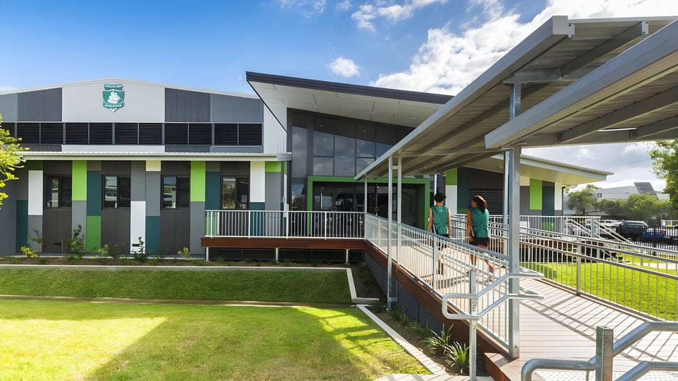 El moderno edificio de varios pisos de la Trinity Bay State High School está rodeado de un prado y un camino con barandillas.