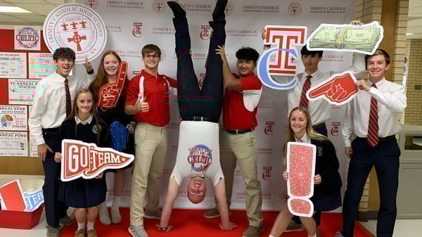 Un grupo de estudiantes posa con vestidos rojos y blancos en el campus de la Trinity Catholic Jr/Sr High School.