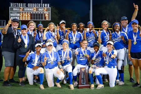Las alumnas de la Trinity Christian Academy celebran su victoria en softball frente a un histórico fondo del centro de la ciudad.