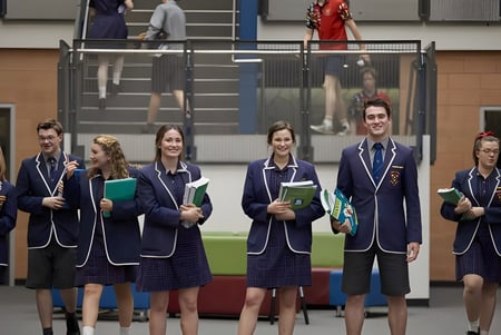 Un grupo de alumnos en uniformes escolares está en el pasillo del campus del Trinity College.