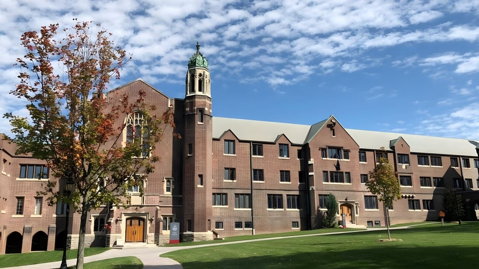 El edificio de ladrillo de varios pisos con una alta torre en el campus de la Trinity College School está rodeado de árboles y césped.