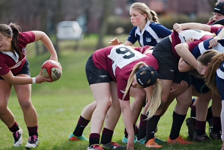 Un grupo de jugadoras de rugby de la Trinity College School está en un agrupamiento en un campo de hierba.