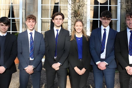 Un grupo de jóvenes está frente a un edificio en el campus de la Trinity School.