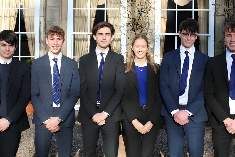 Un grupo de jóvenes está frente a un edificio en el campus de la Trinity School.