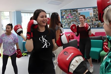 Las alumnas de la Truro High School for Girls entrenan juntas con guantes de boxeo y protección para la cabeza en el sala de entrenamiento.