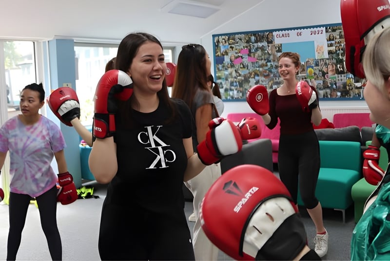 Las alumnas de la Truro High School for Girls entrenan juntas con guantes de boxeo y protección para la cabeza en el sala de entrenamiento.