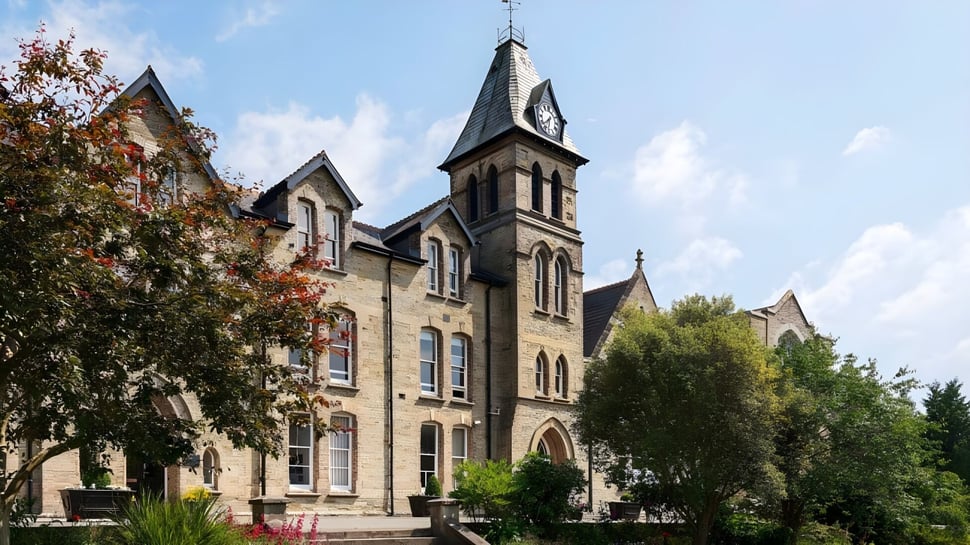 El edificio principal gótico de Truro School está rodeado de árboles y áreas verdes.
