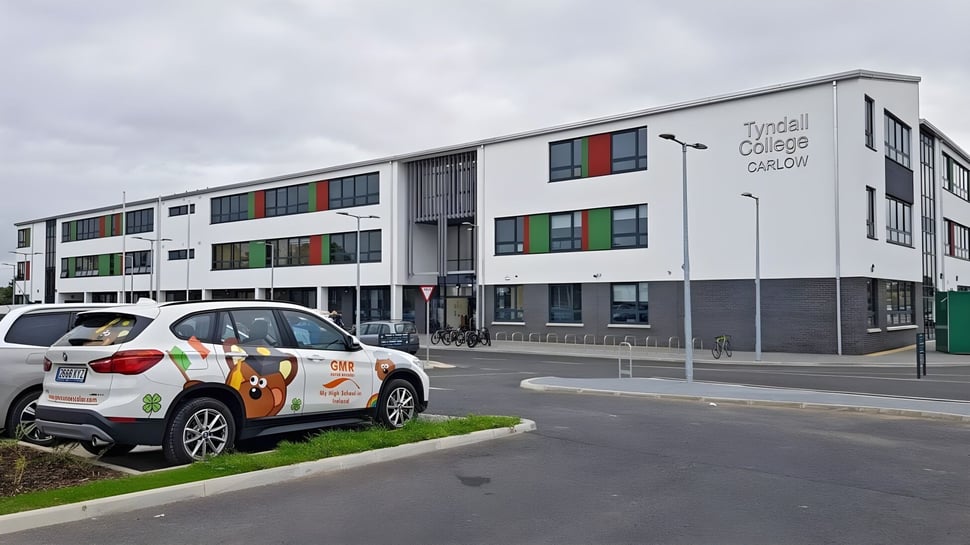 El moderno edificio escolar de varios pisos con ventanas coloridas en el campus del Tyndall College bajo un cielo nublado.