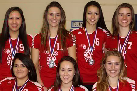 Un grupo de estudiantes de la Ucluelet Secondary School lleva camisetas deportivas rojas con el número 9 y muestra sus medallas.