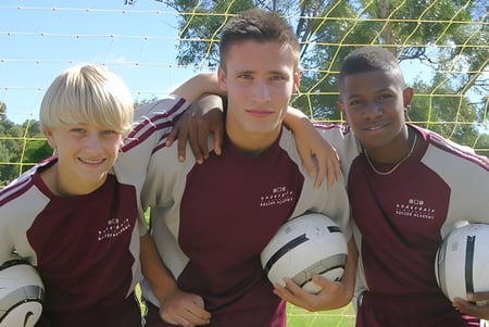 Tres estudiantes de la Underdale High School posan juntos al aire libre en el campo de deportes.