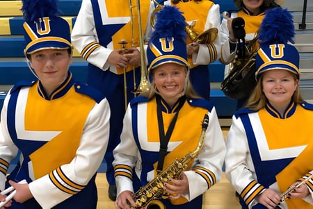 Un grupo de animadoras de la Union High School está en uniformes amarillos y azules en el gimnasio.
