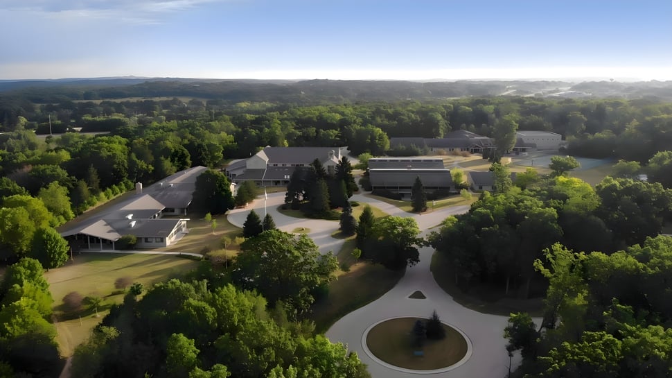 La instalación de la University Lake School está incrustada en un paisaje verde con caminos serpenteantes y una zona central redonda.
