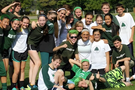Un grupo de estudiantes de la University Lake School posan en uniformes deportivos sobre un campo de césped con árboles al fondo.