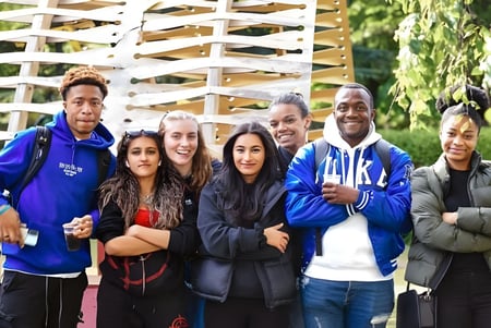 Un grupo de estudiantes se encuentra frente a una estructura de madera en el campus de la University of Westminster.