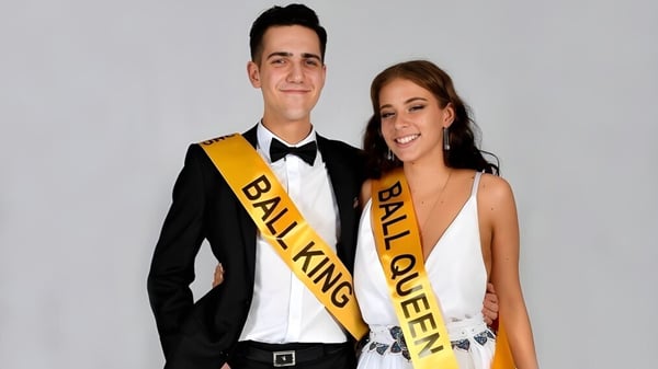 Un hombre con traje negro y una mujer con vestido blanco posan juntos en el Upper Hutt College.