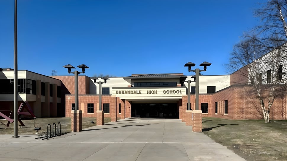 El edificio de ladrillo del Urbandale Community School District está rodeado de un camino pavimentado y farolas.