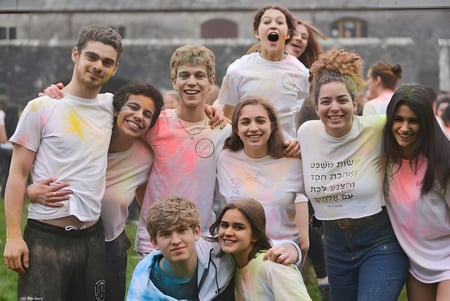 Un grupo de estudiantes está junto en un prado frente a un edificio en el campus del UWC Atlantic College.