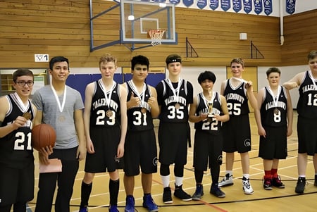 Un grupo de estudiantes de la Valemount Secondary School está junto en el gimnasio frente a una canasta de baloncesto.