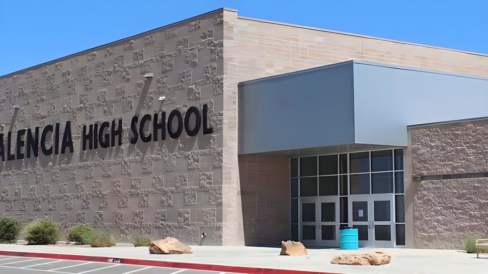 El gran edificio de ladrillo de la Valencia High School con un letrero claramente visible en la fachada bajo un cielo azul.