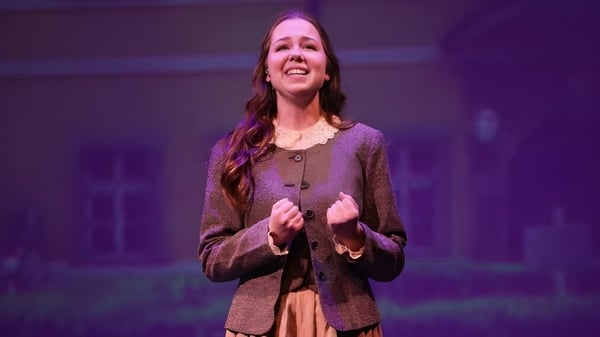 Una estudiante de la Valley Christian High School está en el escenario frente a un fondo morado.