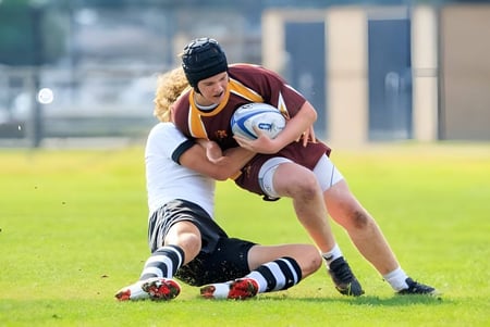 Dos jugadores de rugby en un tackle en el campo de la Valley Christian High School.