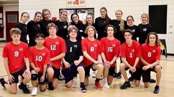 Un grupo de estudiantes de la Valleyview Secondary School en uniformes rojos y negros posan en el gimnasio frente a un cartel de Go Vikings.