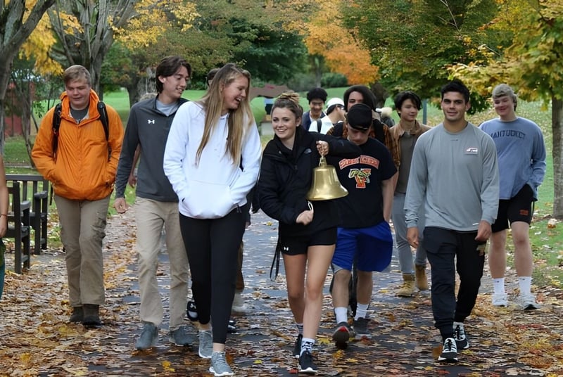 Un grupo de estudiantes de la Vermont Academy camina juntos por un camino con hojas de otoño coloridas.