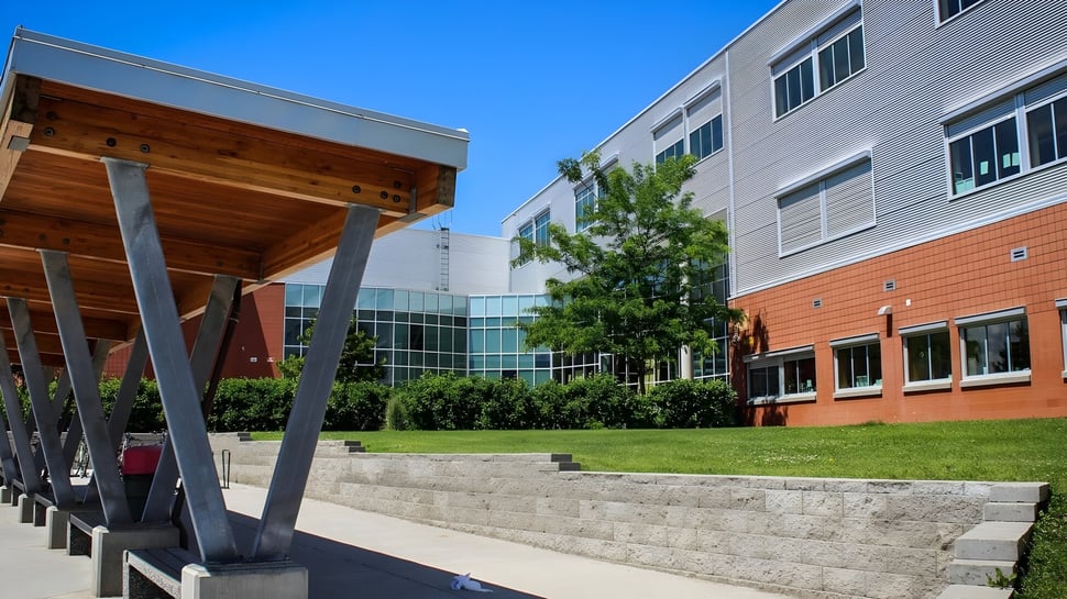 El moderno edificio de la Vernon Secondary School con voladizo de madera y ventanas de vidrio está rodeado de un prado con escaleras de piedra.