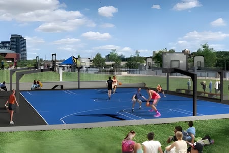 Estudiantes de la Victoria Park High School juegan baloncesto en la colorida cancha exterior con edificios y áreas verdes al fondo.